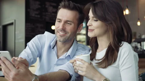 Attractive young couple using smartphone at cafe Stock Footage 64649439