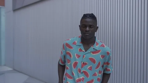 Attractive young dark skinned afro guy posing walks looking at the camera  Stock Footage 110884904