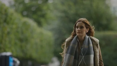 Attractive young female checking her phone whilst listening to music Stock Footage 80321496