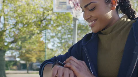Attractive young female checking her digital fitbit on her wrist in a basketball Stock-Footage 219472602