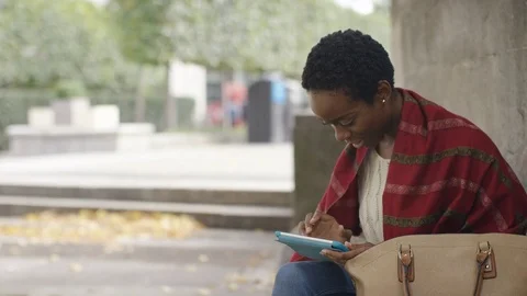 Attractive young female outdoors using a digital tablet, with space for text Stock Footage 80300187