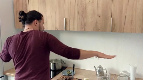 Attractive young funny man dancing and singing with ladle while while cooking in Stock Footage 82414846