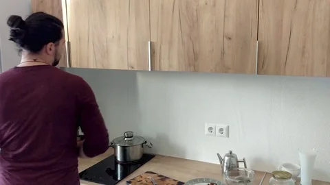 Attractive young funny man dancing and singing with ladle while while cooking in Stock Footage 82416116