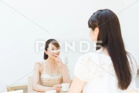 Attractive young girls chatting over a cup of coffee Stock Photos