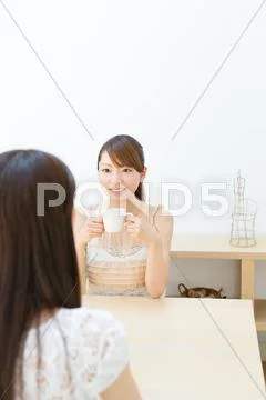 Attractive young girls chatting over a cup of coffee Stock Photos