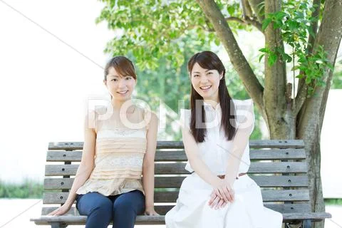 Attractive young girls sitting in a park Stock Photos