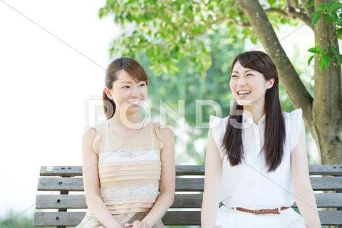Attractive young girls sitting in a park Stock Photos