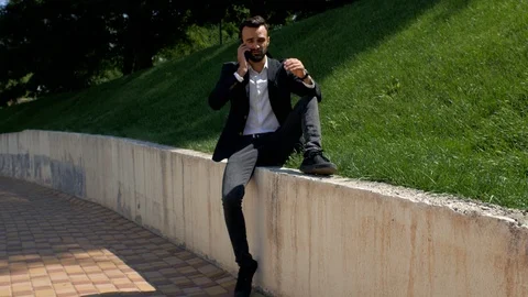 Attractive young guy with a beard in a classic suit  talking on the phone Stock Footage 113965570