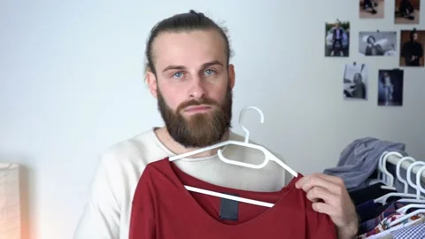 Attractive young guy is looking into the mirror Putting together outfit Stock Footage 147897999