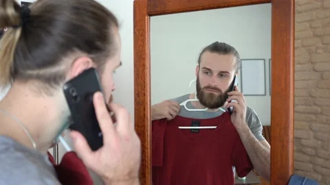 Attractive young guy,  Putting together an outfit Talking on smartphone Stock Footage 147894662