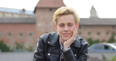 Attractive young guy sits propping his head with his hand and smiling. the guy Video stock 126576202