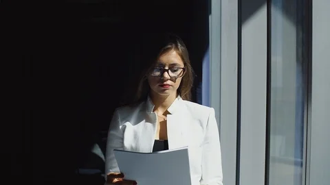 Attractive young lady with documents in her hands stands near window Stock Footage 101080081