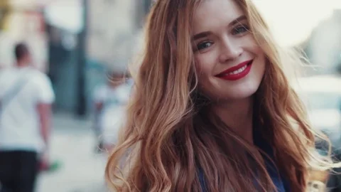 Attractive young lady is walking down city street, turns to camera and smiles Stock Footage 71769724