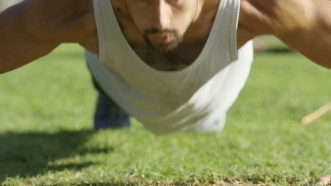 Young Caucasian Male in Sportswear Doing Push Ups on a Green