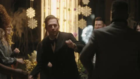 Attractive young man dancing in merry Xmas party and flirting with women Видео 227003020