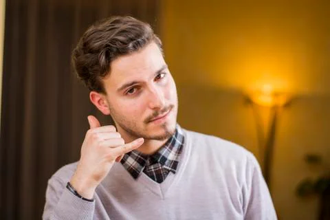 Attractive young man doing call me sign with hand and fingers Stock Photos