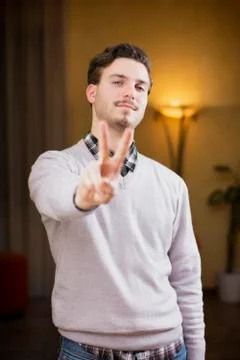 Attractive young man doing peace or victory sign Foto stock