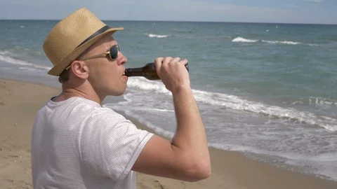 Attractive young man drinks beer and watches the sea Stock Footage 123016357