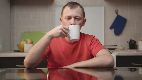 Attractive young man drinks from a white mug Stock Footage 130666926