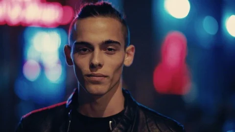 Attractive young man in a leather jacket happily smiles straight to camera Stock Footage 90861882