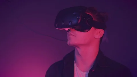 Attractive young man looking around in virtual reality glasses. Cyber neon Stock-Footage 113192957