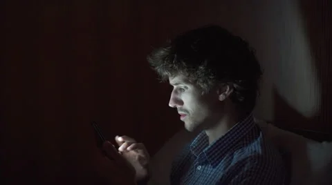 Attractive Young Man Lying on Sofa at Night and Illuminated by Light from Screen Stock Footage 67750346