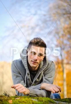 Attractive young man outdoors in nature lying on moss Stock Photos