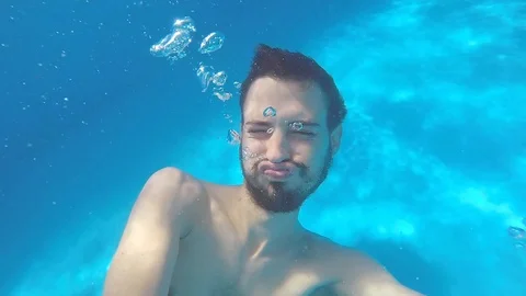 Attractive young man playing in a pool in summer 動画素材 106310100