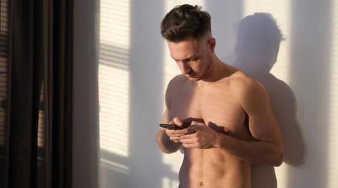Attractive young man shirtless using cell phone Stock Photos