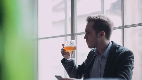 Attractive young man sits alone in the bar, uses his phone, takes photo. Stock Footage 74806987