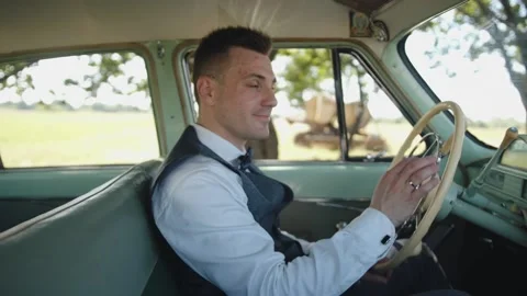 Attractive young man sits behind the wheel of a retro Volga Gaz 21. Success 库存影片 166947153