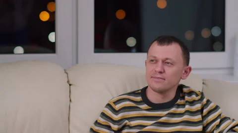 Attractive young man sitting on the sofa and watching TV, copy space Stock Footage 132826235
