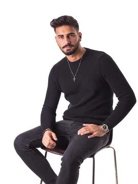 Attractive young man sitting on stool, wearing wool sweater Stock Photos