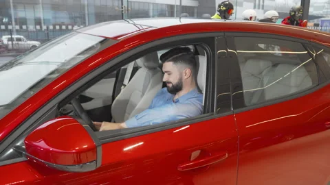 Attractive young man smiling to the camera sitting in a new car at the Stock Footage 147547598