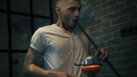 Attractive young man is smoking a hookah after busy day Stock Footage 93826238