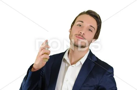 Attractive young man spraying perfume, using fragrance Stock Photos