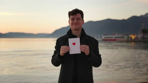 Attractive young man in stylish coat holds Love letter. Valentine's day, St Vídeo Stock 229510150
