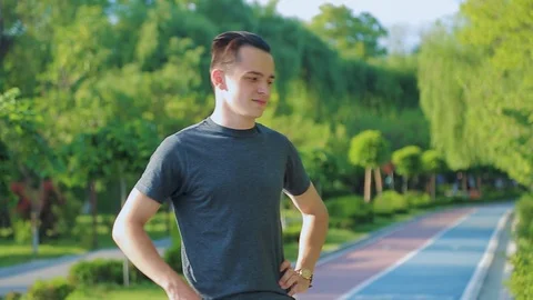 Attractive young man talks on his cell phone as he walks in a park Stock Footage 90300103