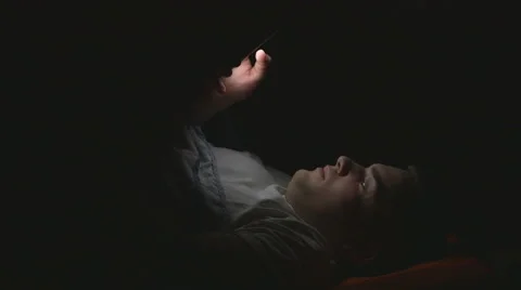 Attractive young man using a smart phone in bed Stock Footage 61633156