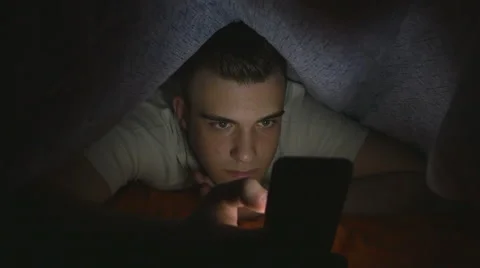 Attractive young man using a smart phone in bed Stock Footage 61633311