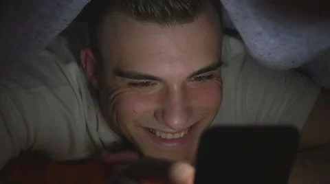 Attractive young man using a smart phone in bed Stock Footage 61633528