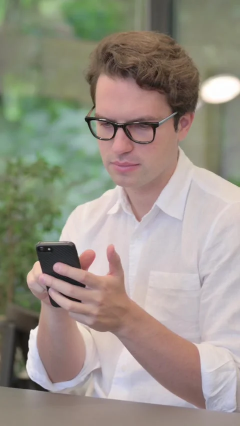 Attractive Young Man Using Smartphone in Modern Office, Vertical Video Stock Footage 340032494
