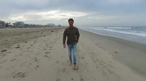 An attractive young man walking on the beach in Santa Monica, California, at Stock Footage 68051077