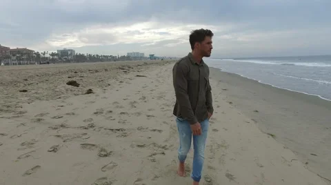 An attractive young man walking on the beach in Santa Monica, California, at Stock Footage 68051087