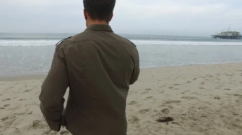 An attractive young man walking on the beach in Santa Monica, California, at Stock Footage 68051132