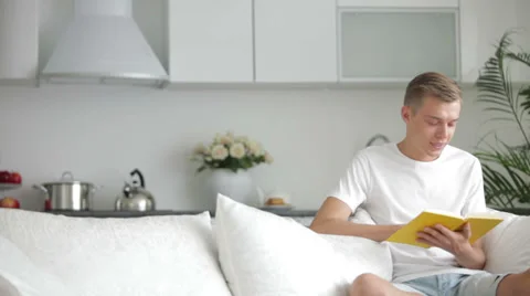 Attractive young men sitting on sofa and reading book Stock Footage 27692046