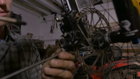 An attractive young millennial man makes adjustments to disc brakes on bike Stock Footage 69908991