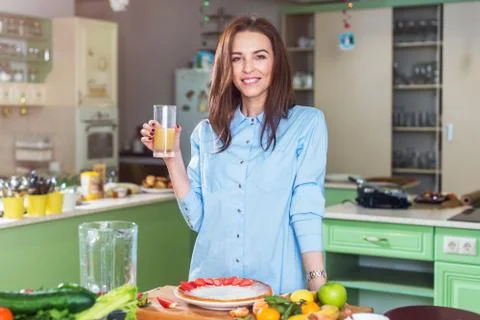 Attractive young model posing in kitchen holding a glass of juice in Provence Stock Photos