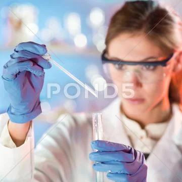 Attractive young scientist pipetting. Stock Photos