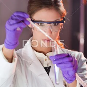Attractive young scientist pipetting. Stock Photos